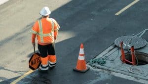 Construction crew member in orange shirt holding a stop sign