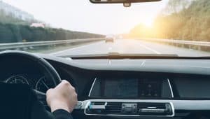 Closeup of hand on a steering wheel looking with road in the background