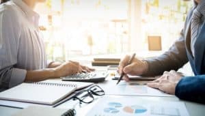 Two people working at a desk with various papers