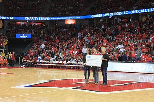 Gruber law team giving a big check to a happy Bucks fan on the court