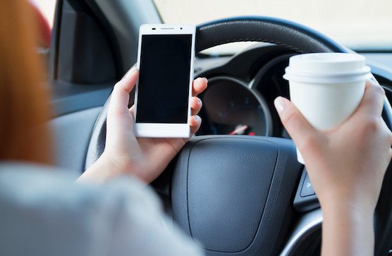 person texting and drinking coffee while driving distracted