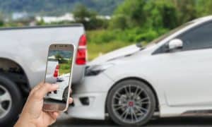 Someone using a cell phone to take a picture of a two car accident