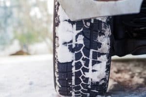 Car tires on winter road covered with snow. Vehicle on snowy alley in the morning at snowfall