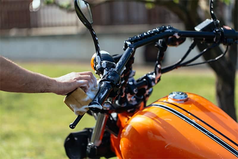 person washing orange motorcycle