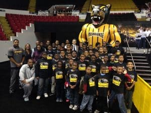 Group photo of middle school children and volunteers at a milwaukee basketball game