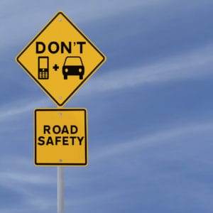 A yellow safety don't text and drive sign