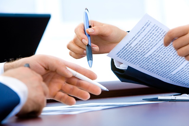 close up of two men at a table look through documents