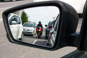 A motorcyclist in a car rearview mirror that could cause an accident. A Madison, WI, motorcycle accident lawyer can help you recover compensation.