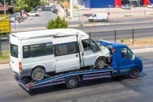 A tow truck removes a damaged delivery van from the scene of an accident.