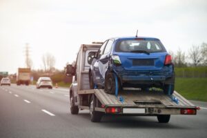 A tow truck removes a car from the scene of a delivery truck accident.